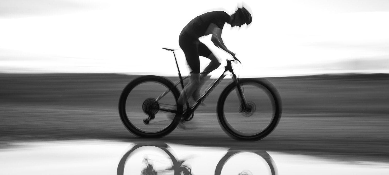 A man riding the Orbea Alma mountain bike, photographed in black and white. 