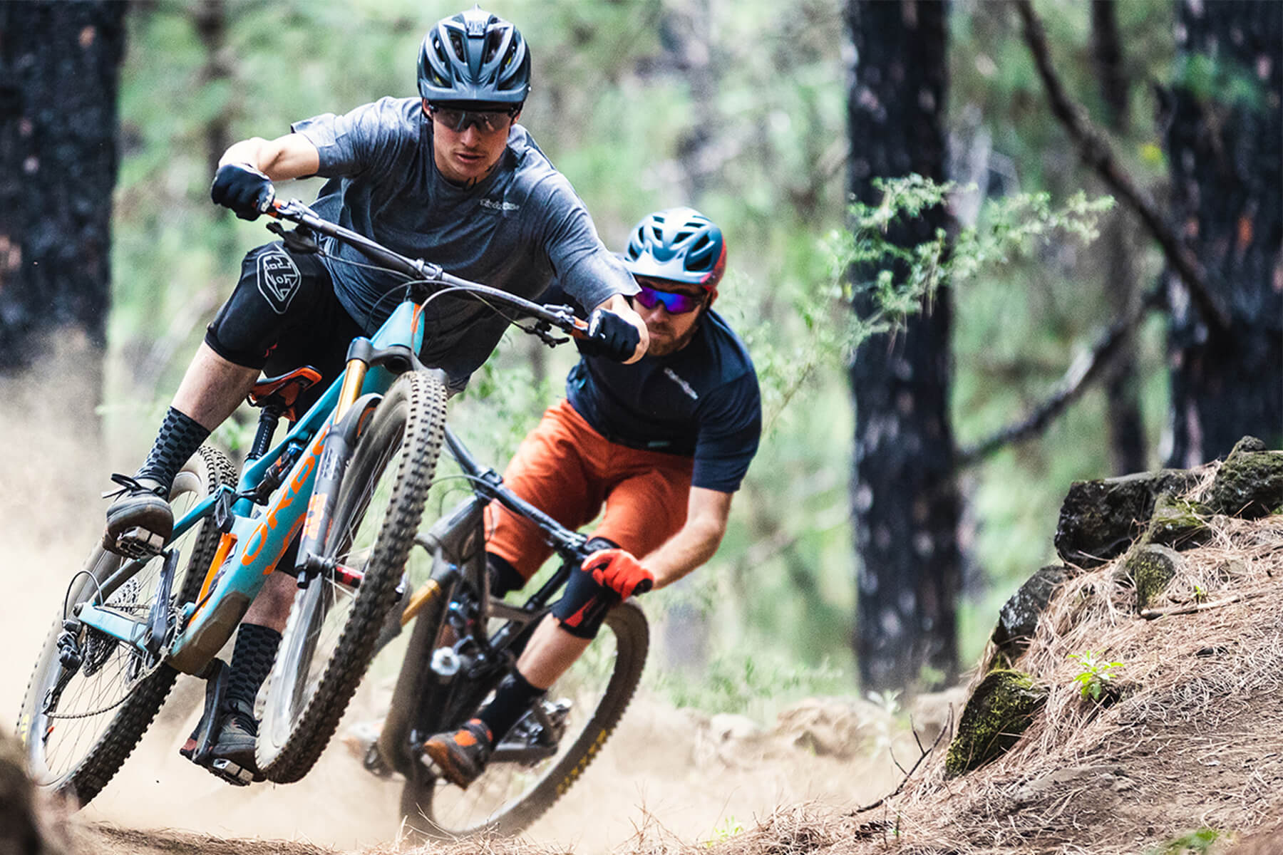 Two men, riding the Orbea Occam mountain bike through a forest. 