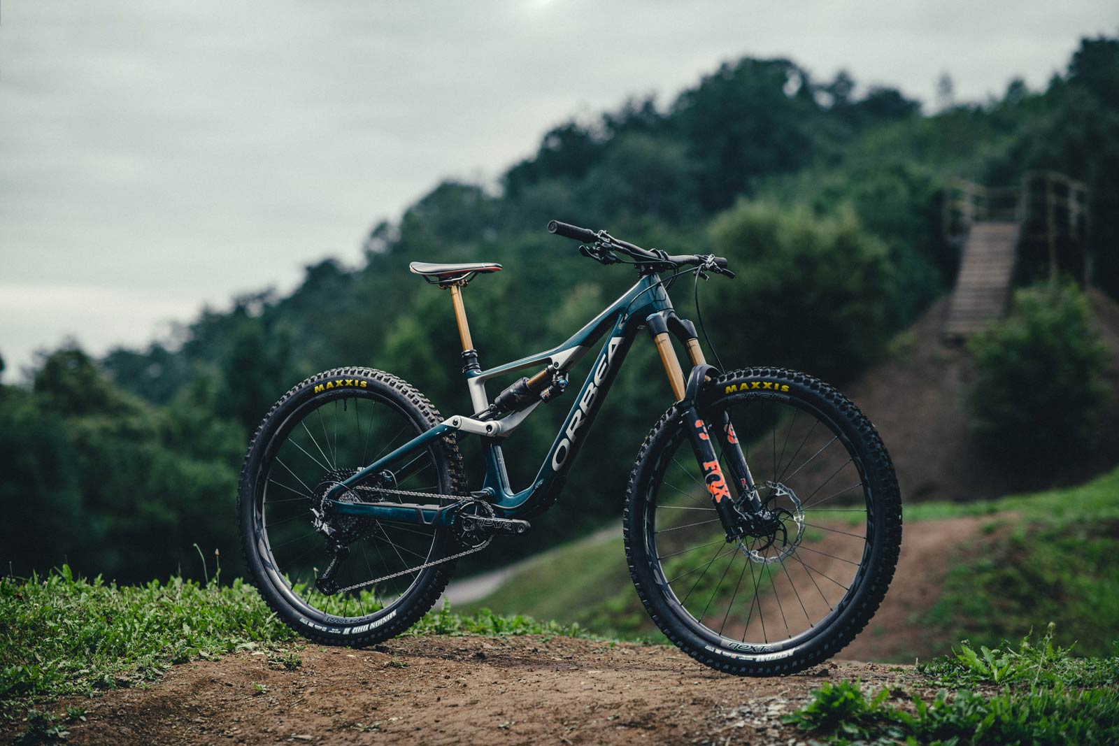 The Orbea Rallon mountain bike staged in a forest, on a dirt trail.