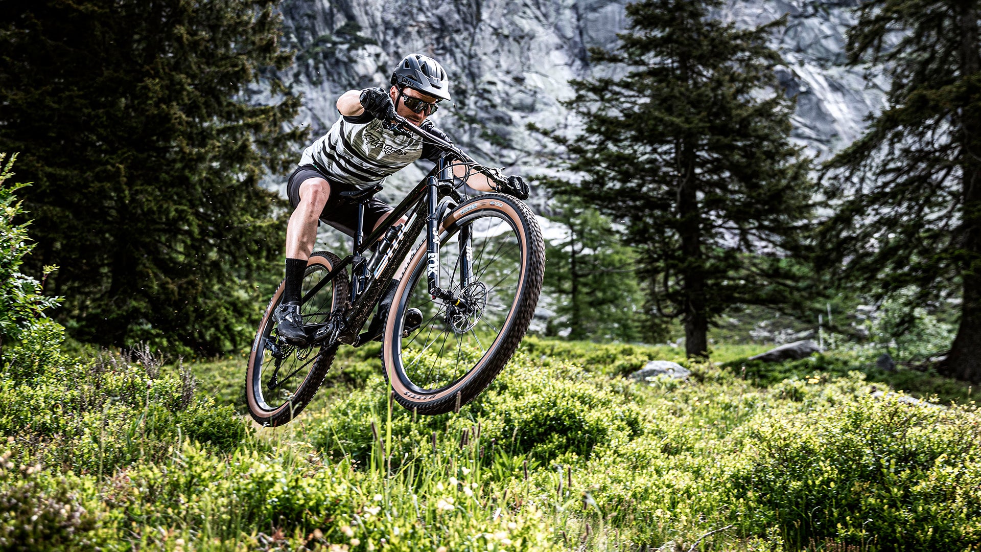 A man riding the BMC Fourstroke AMP electric mountain bike up a hill in the mountains. 