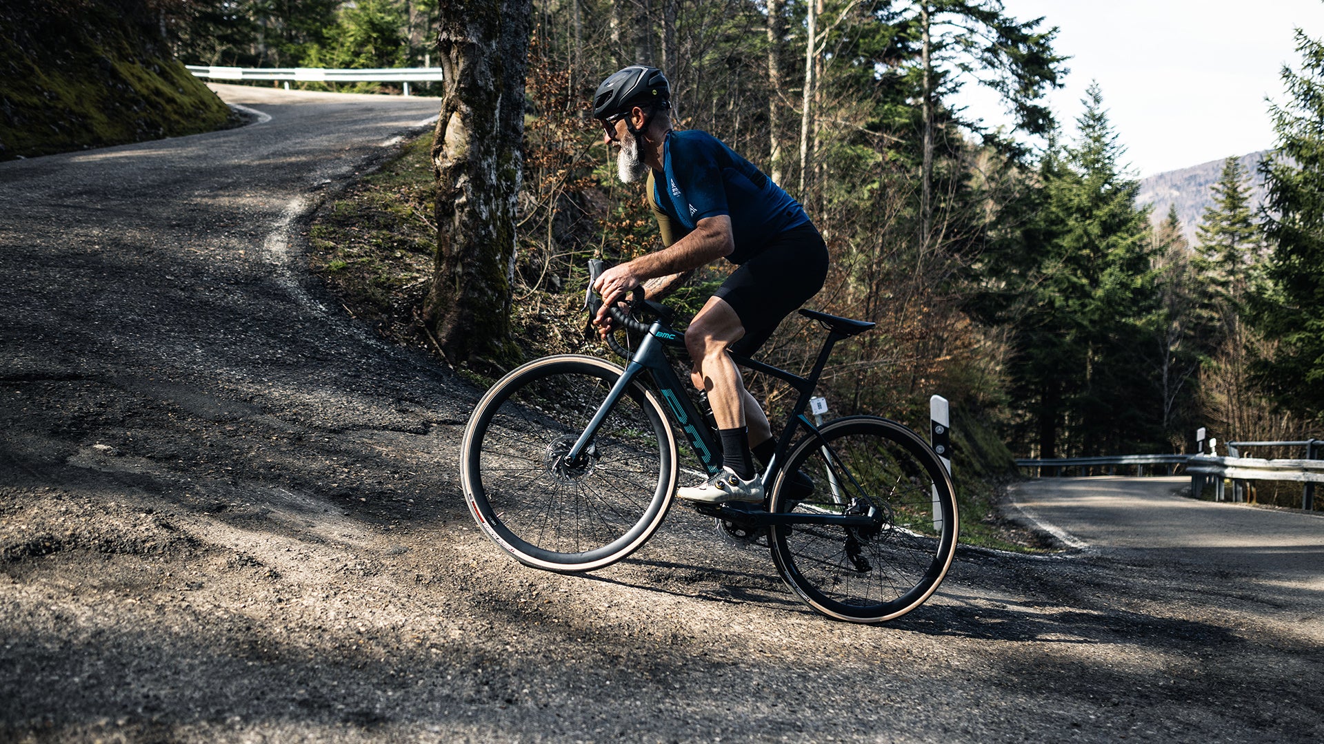 a man riding a BMC Roadmachine AMP electric Road bike up a hill