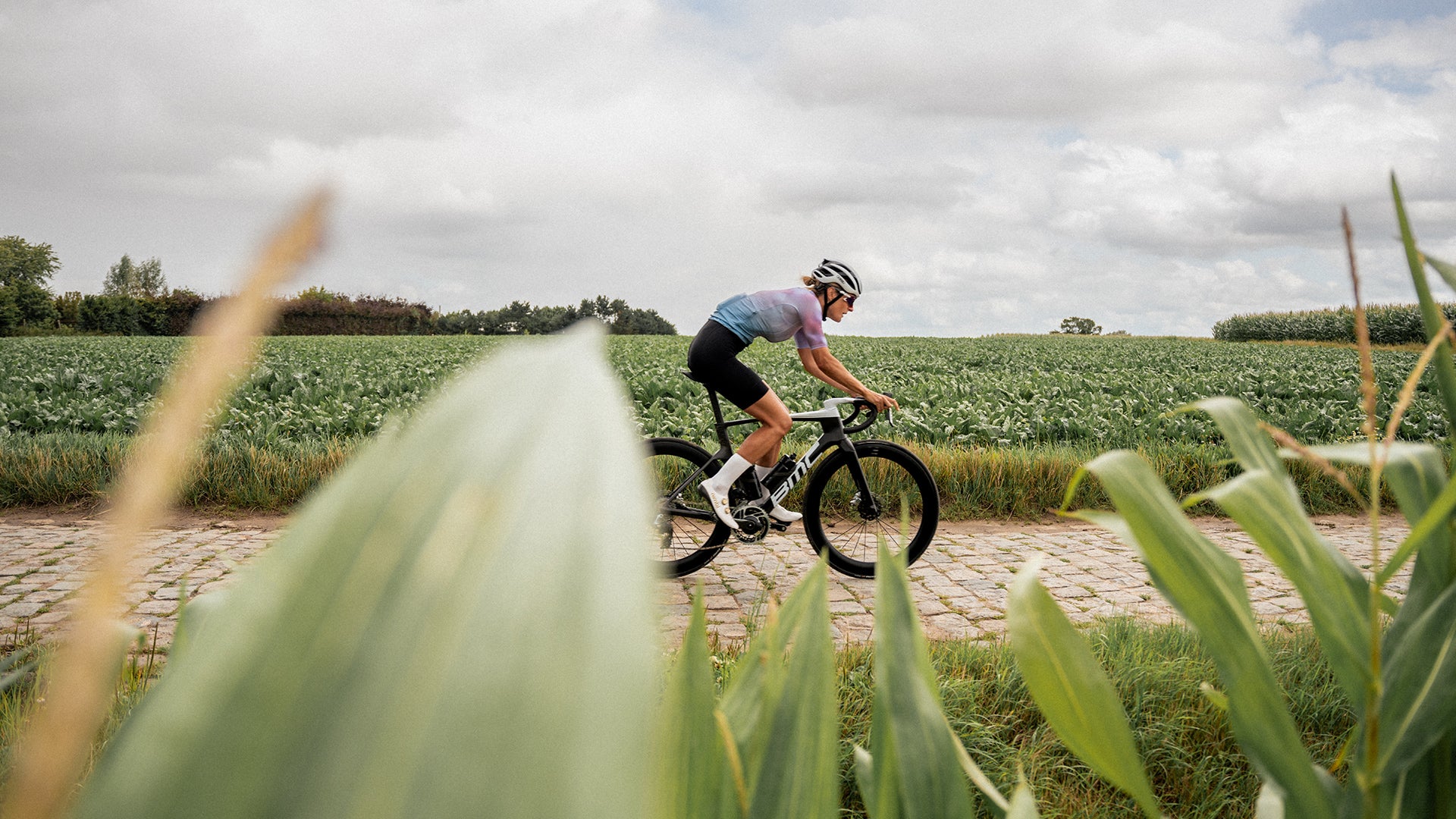 A woman riding a BMC Teammachine R on a cobblestone road. 