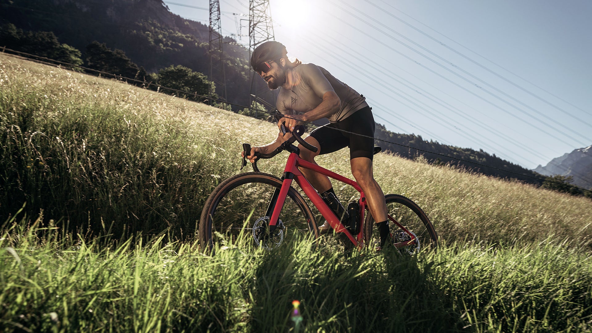 A man riding the BMC URS AMP electric gravel bike up a hill in the mountains. 