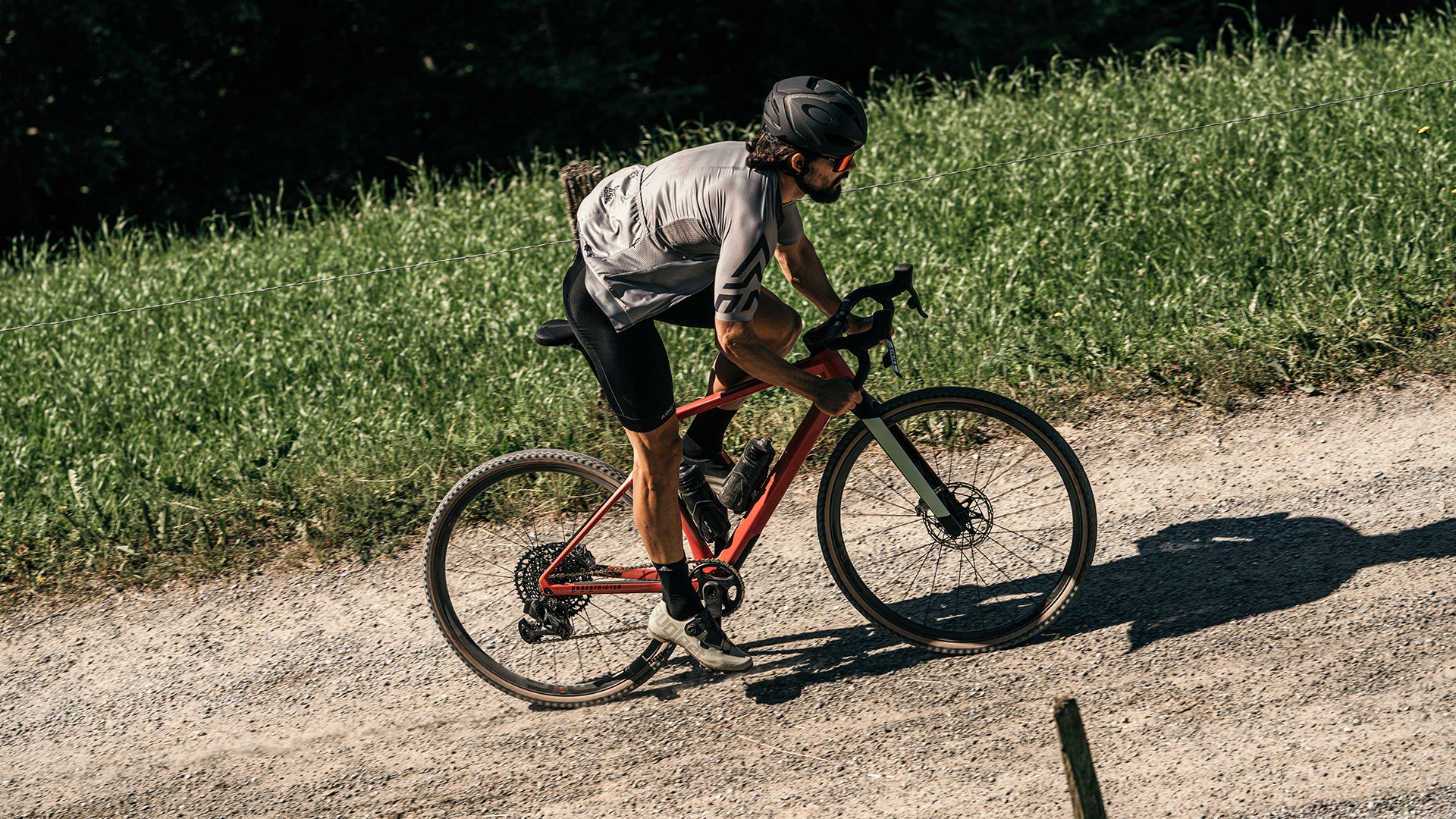 A man riding the BMC URS AMP electric gravel bike up a hill in the mountains. 