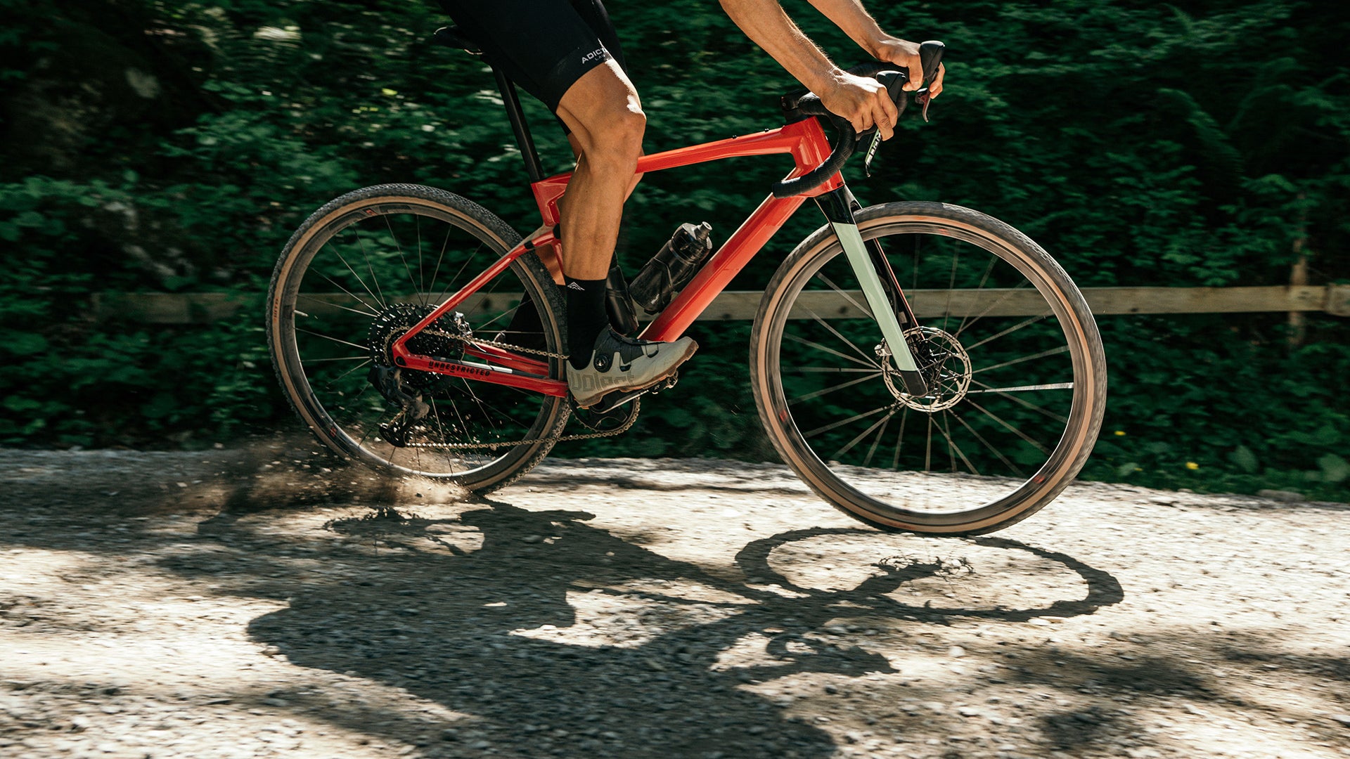 A man riding the BMC URS AMP electric gravel bike up a hill in the mountains. 