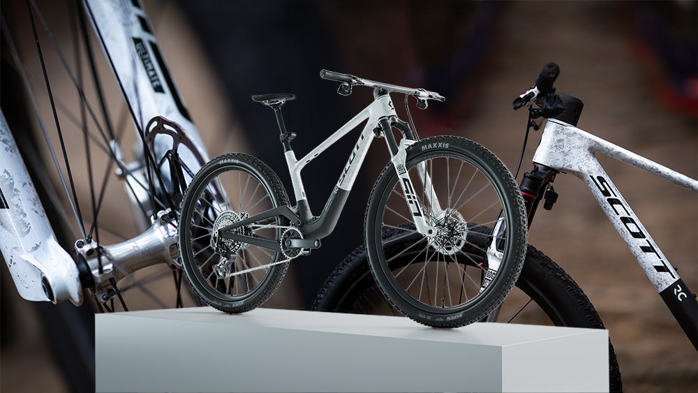 White bicycle with black components on a white platform against a blurred background
