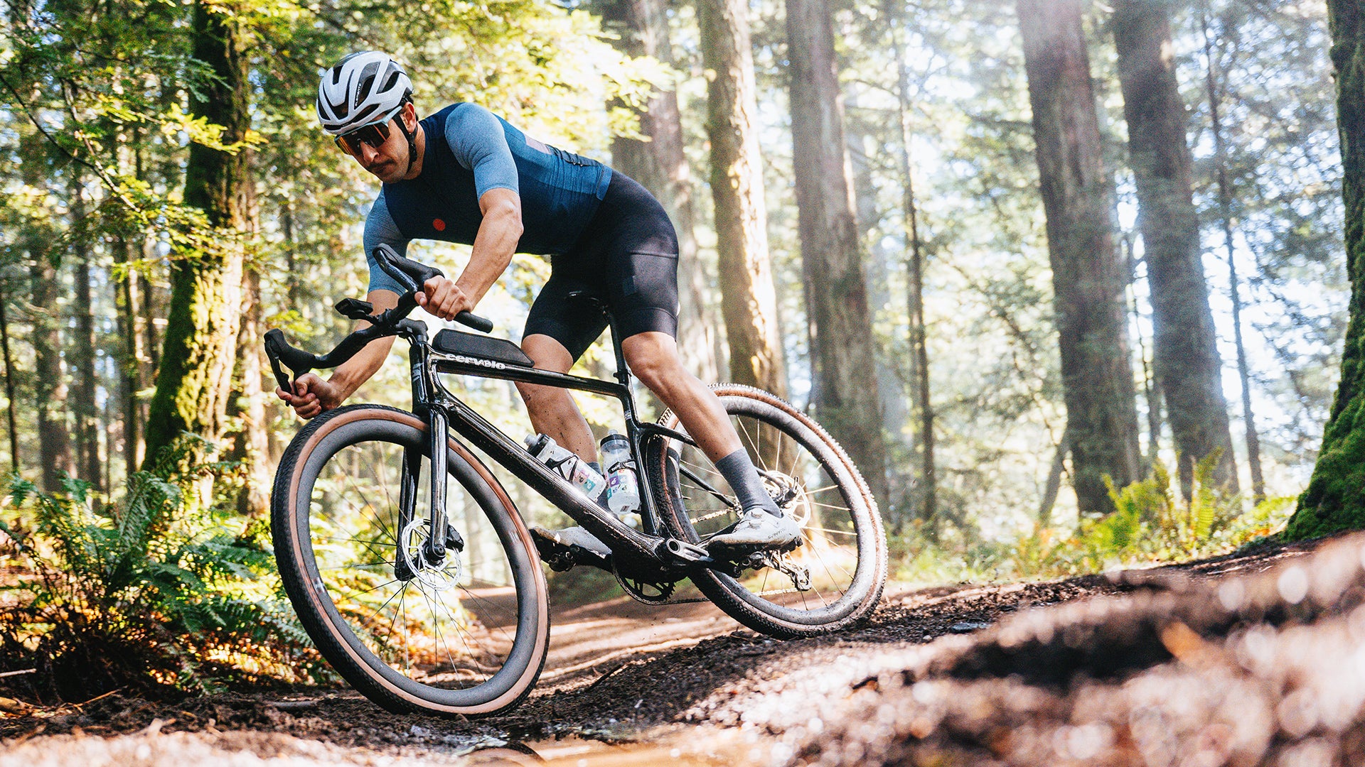 a man riding the cervelo aspero gravel bike through a muddy forest