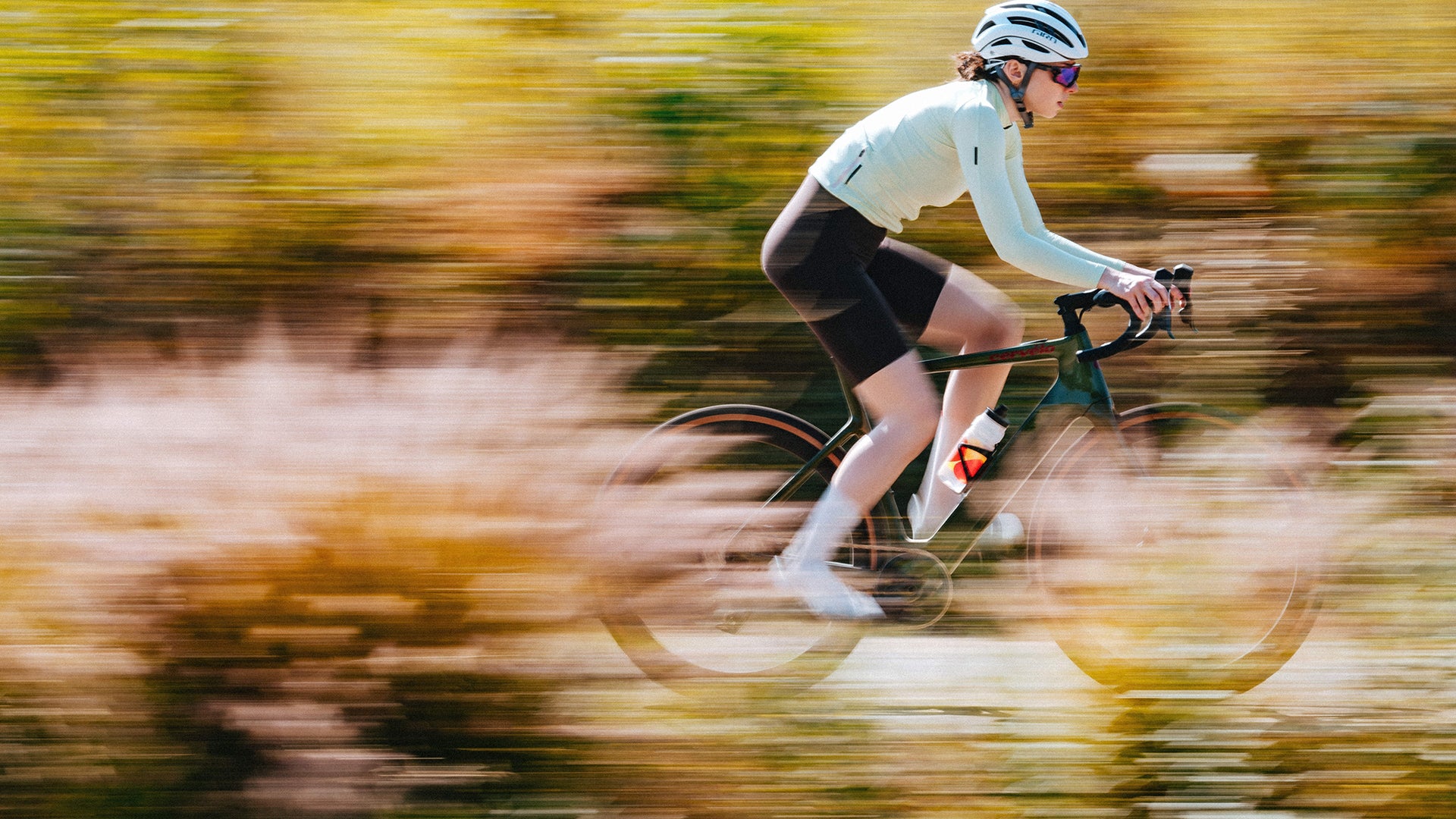 A woman riding the cervelo Rouvida Electric bike against tall grass. 