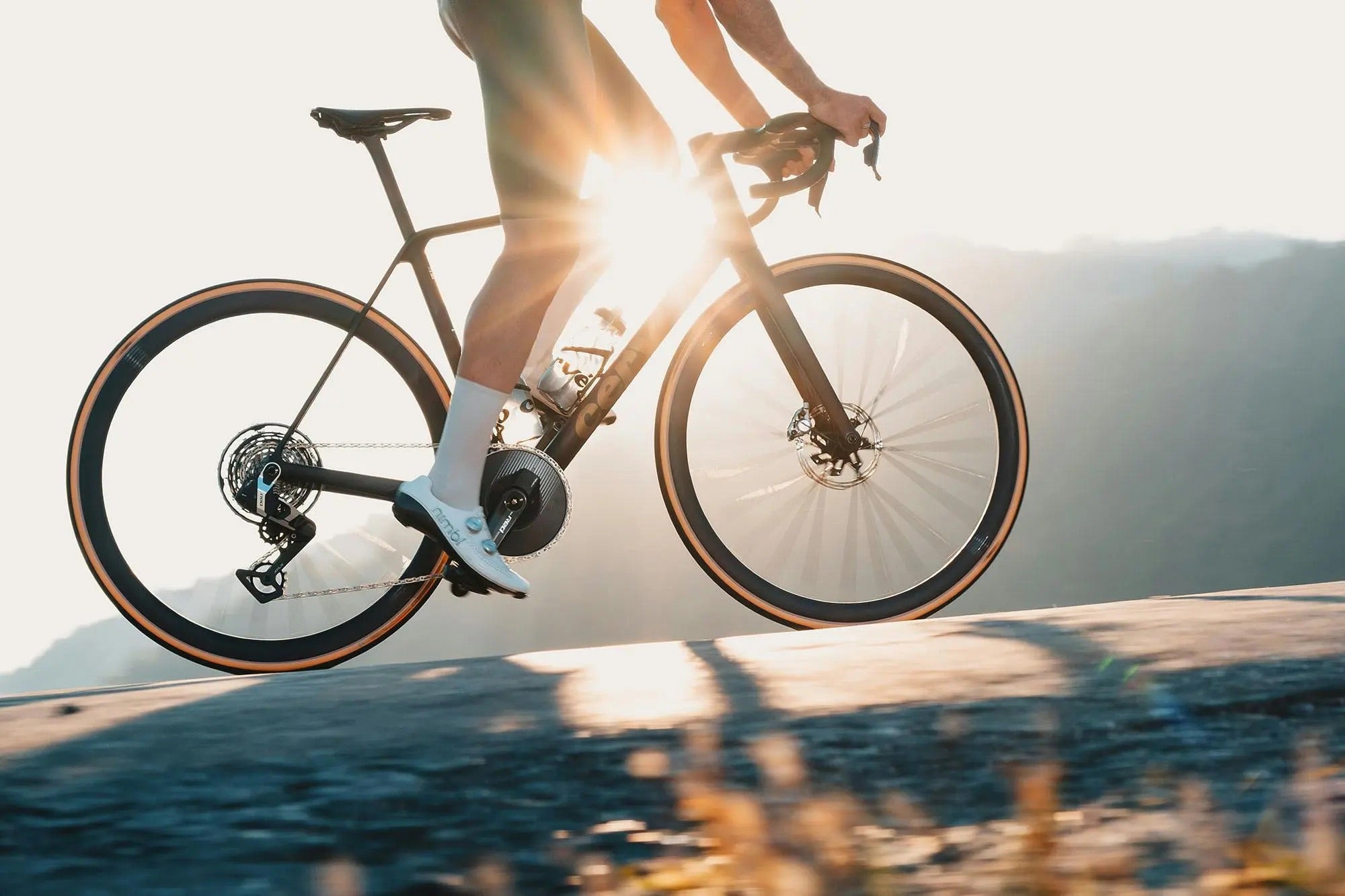 a person riding the Cervelo R5 road bike up the hill with the sun in the background.