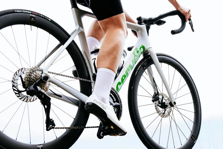 A silver and green Cervelo road bike being ridden by a man. 
