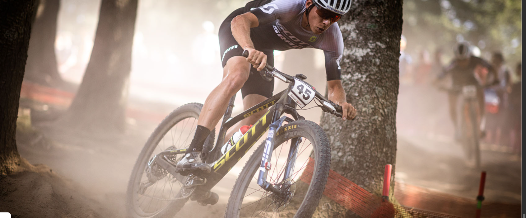 A man riding the Scott Spark RC mountain bike in a race through a forest. 