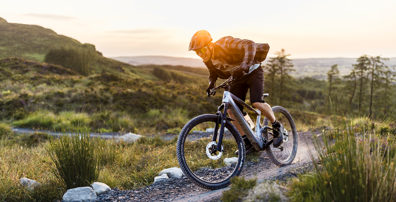 A man riding on a Scott Lumen Electric Mountain bike sold at Contender Bicycles. 