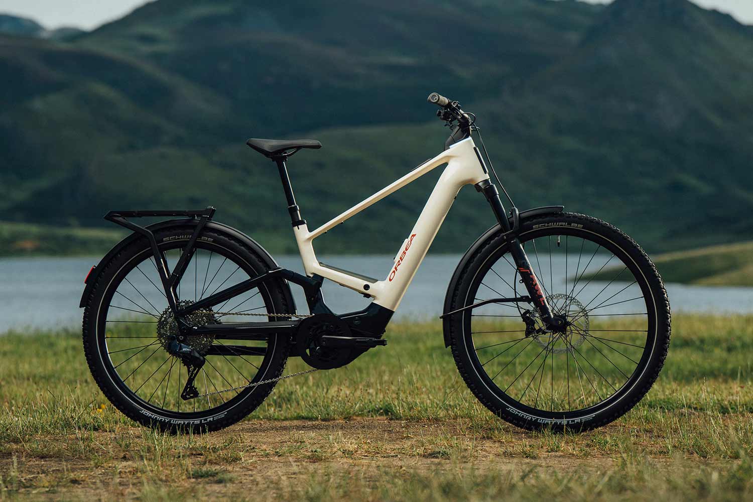 Electric bike on a grassy area with a mountainous background.