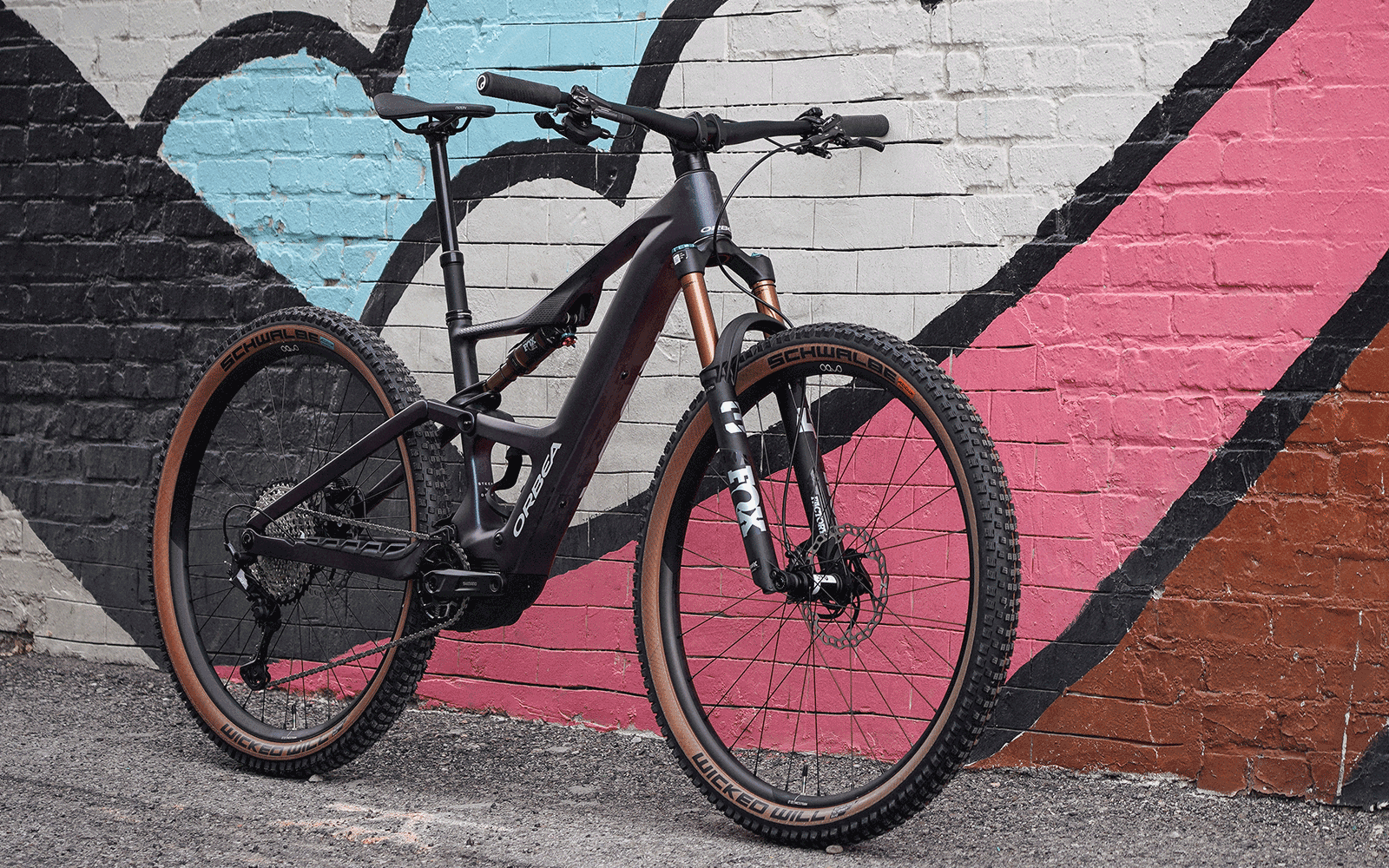 2025 Orbea Rise E-Mountain bike against a colorful wall.