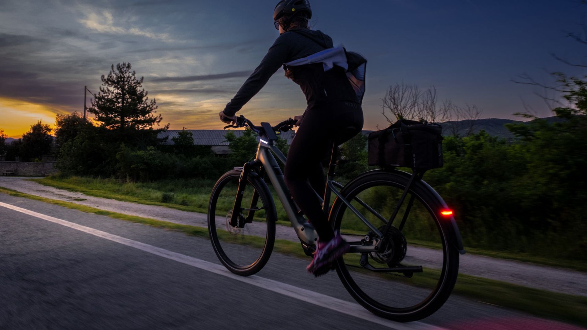 A woman riding an orbea kemen electric bike at night.