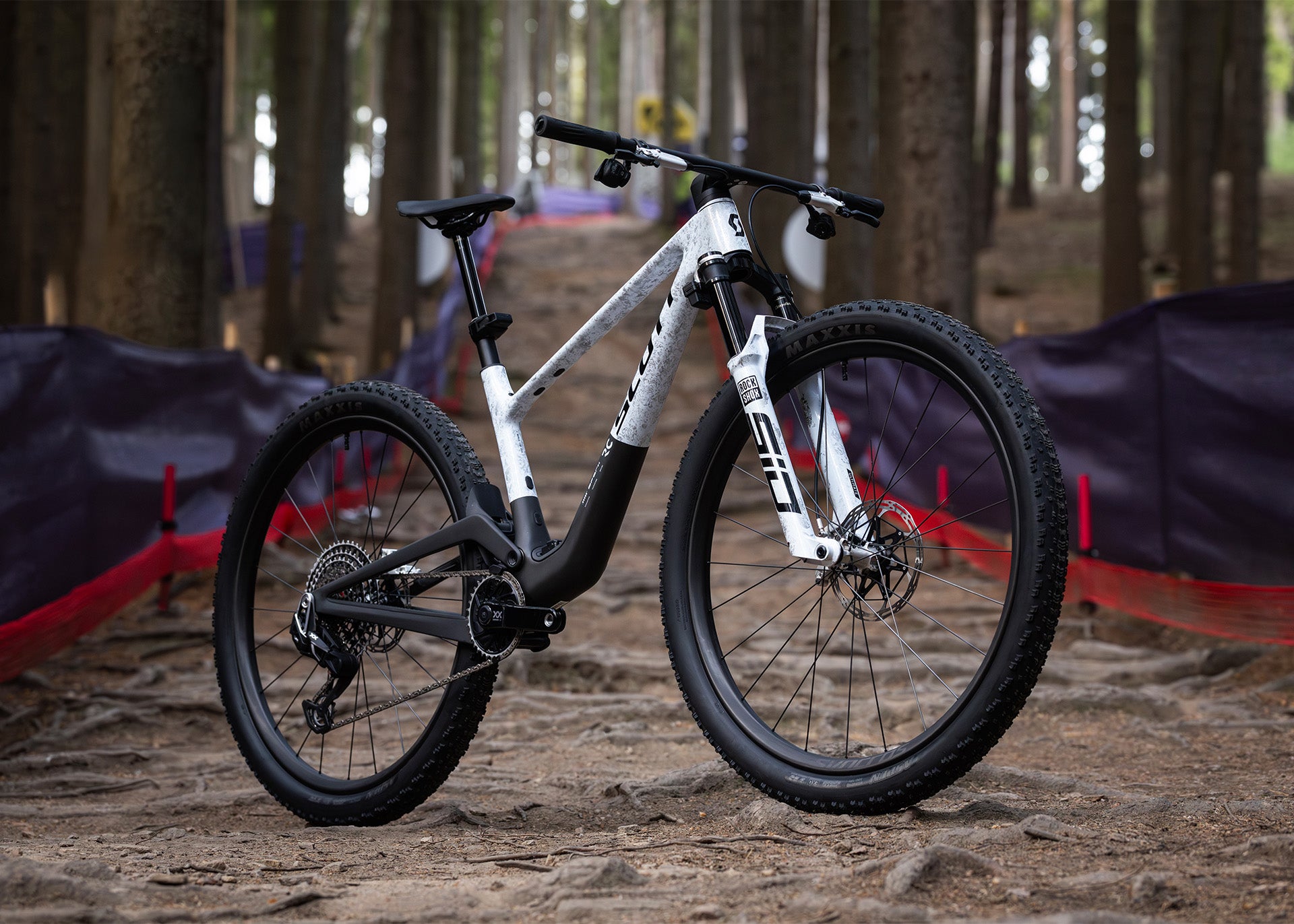 White mountain bike on a dirt path with trees in the background