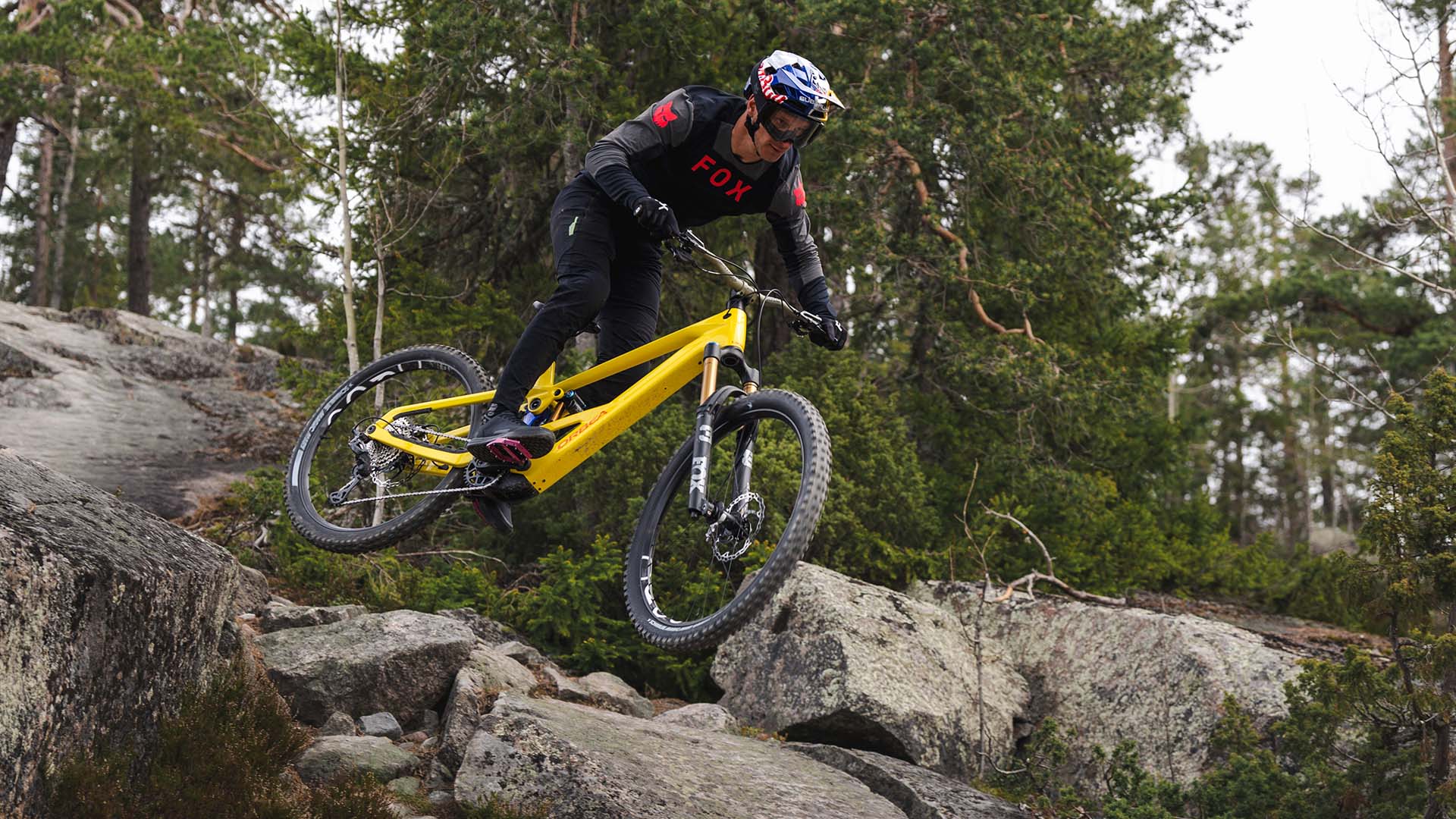 Yellow Orbea Wild Lt being jumped over rocks.