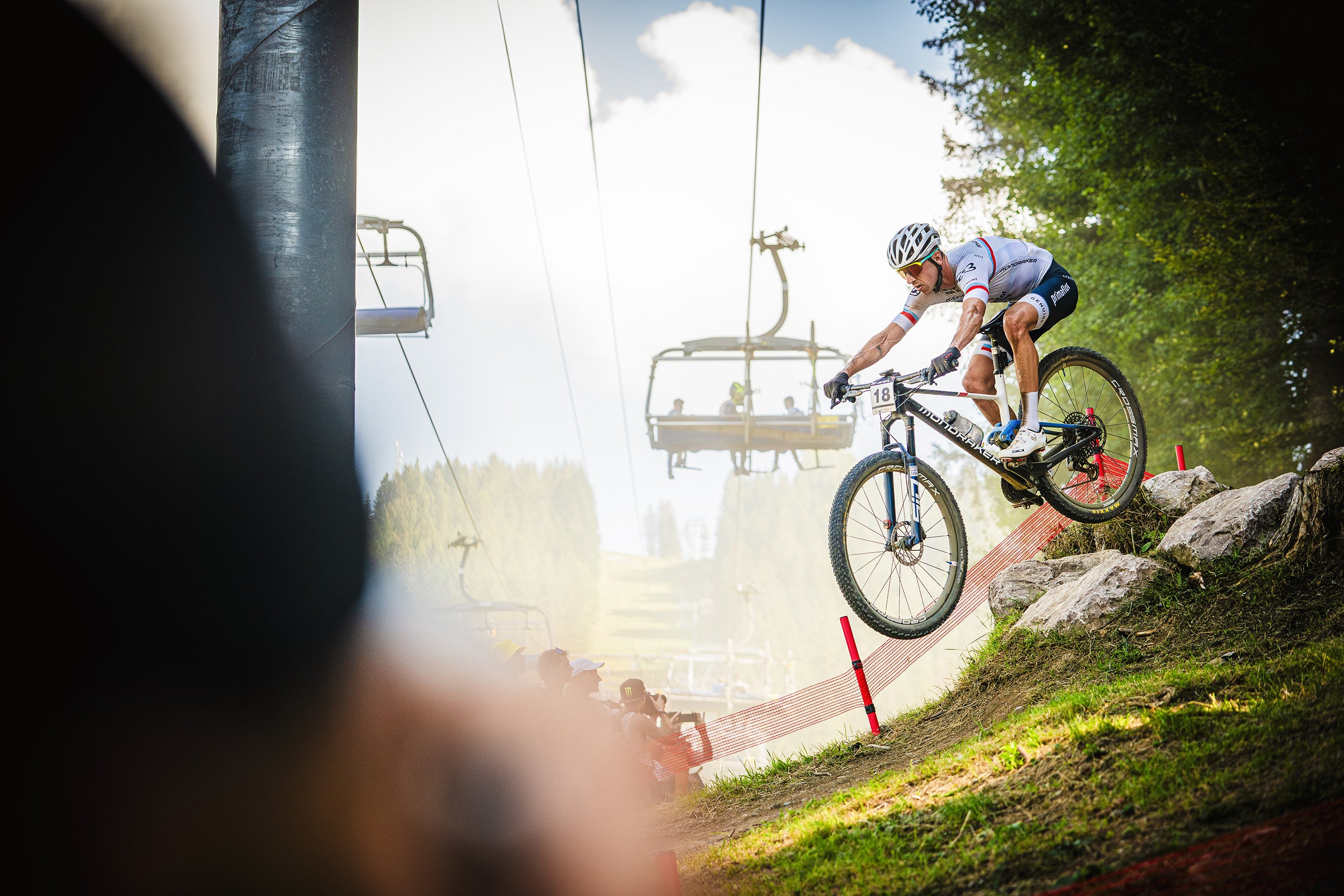 A man riding the Mondraker F Podium on a cross country race course. Available at Contender Bicycles. 