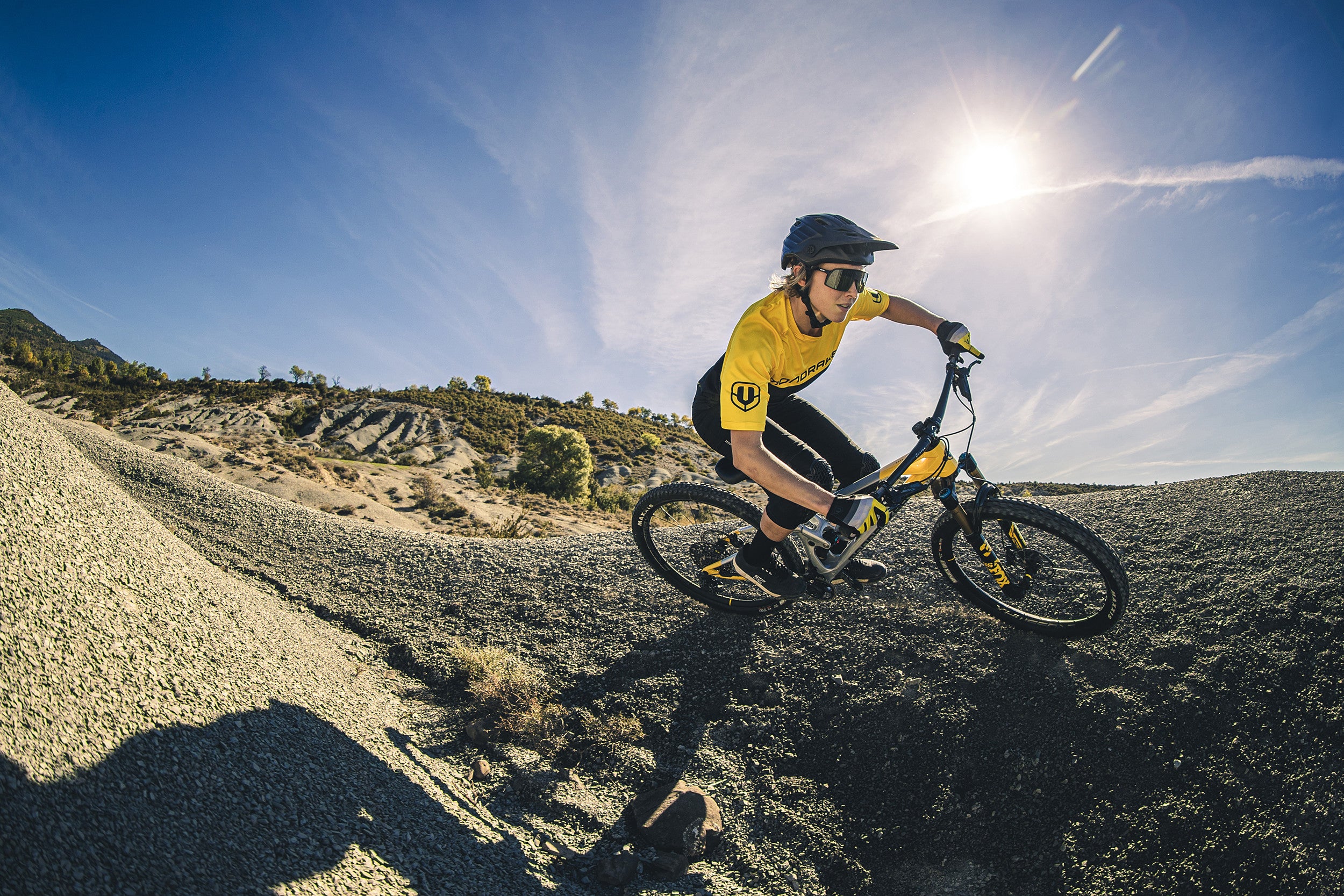 A Woman riding the Mondraker Raze Trail Bike going into a corner, available at Contender Bicycles. 