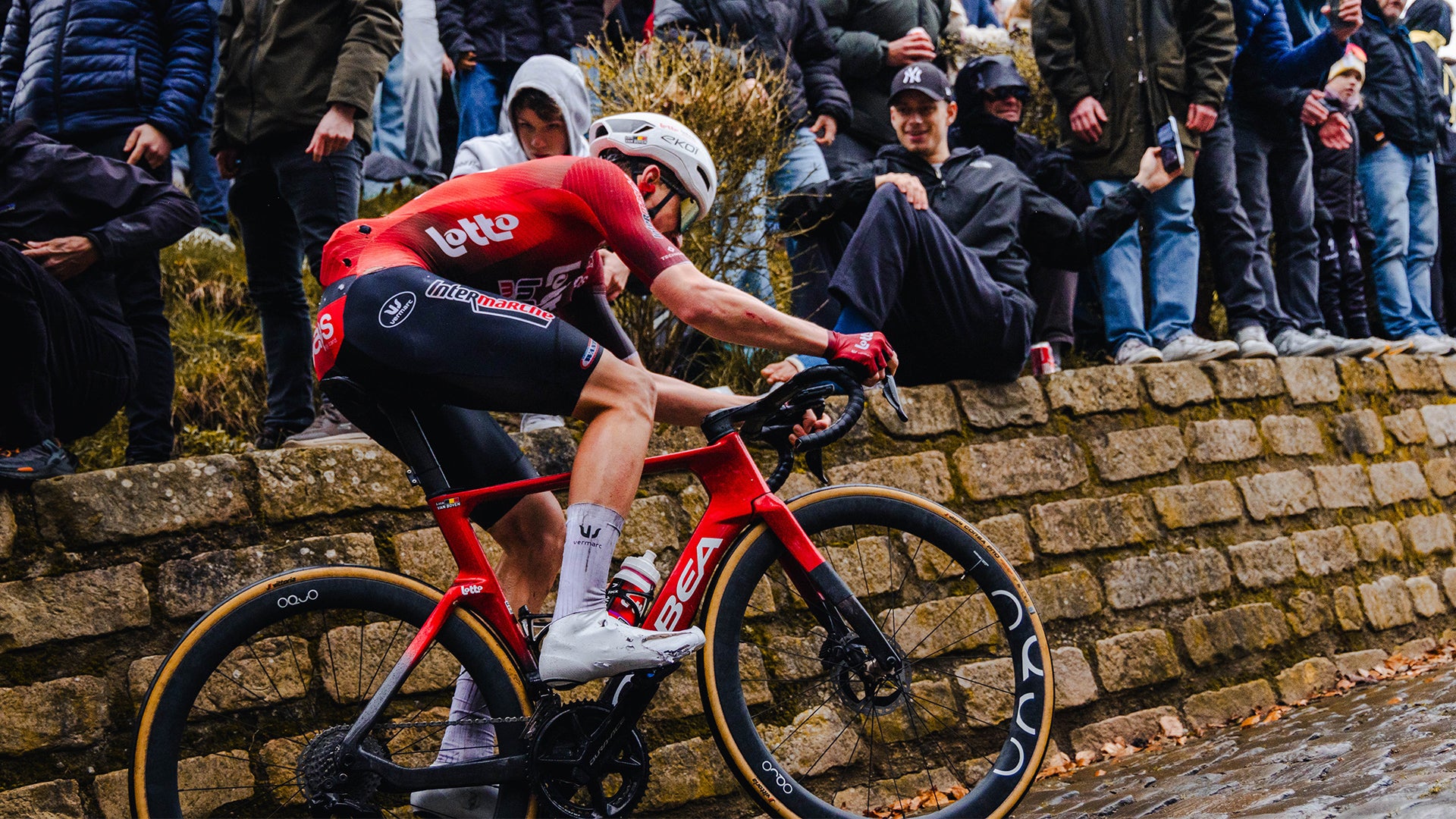 A man in a read jersey riding a red orbea road bike in a race. 
