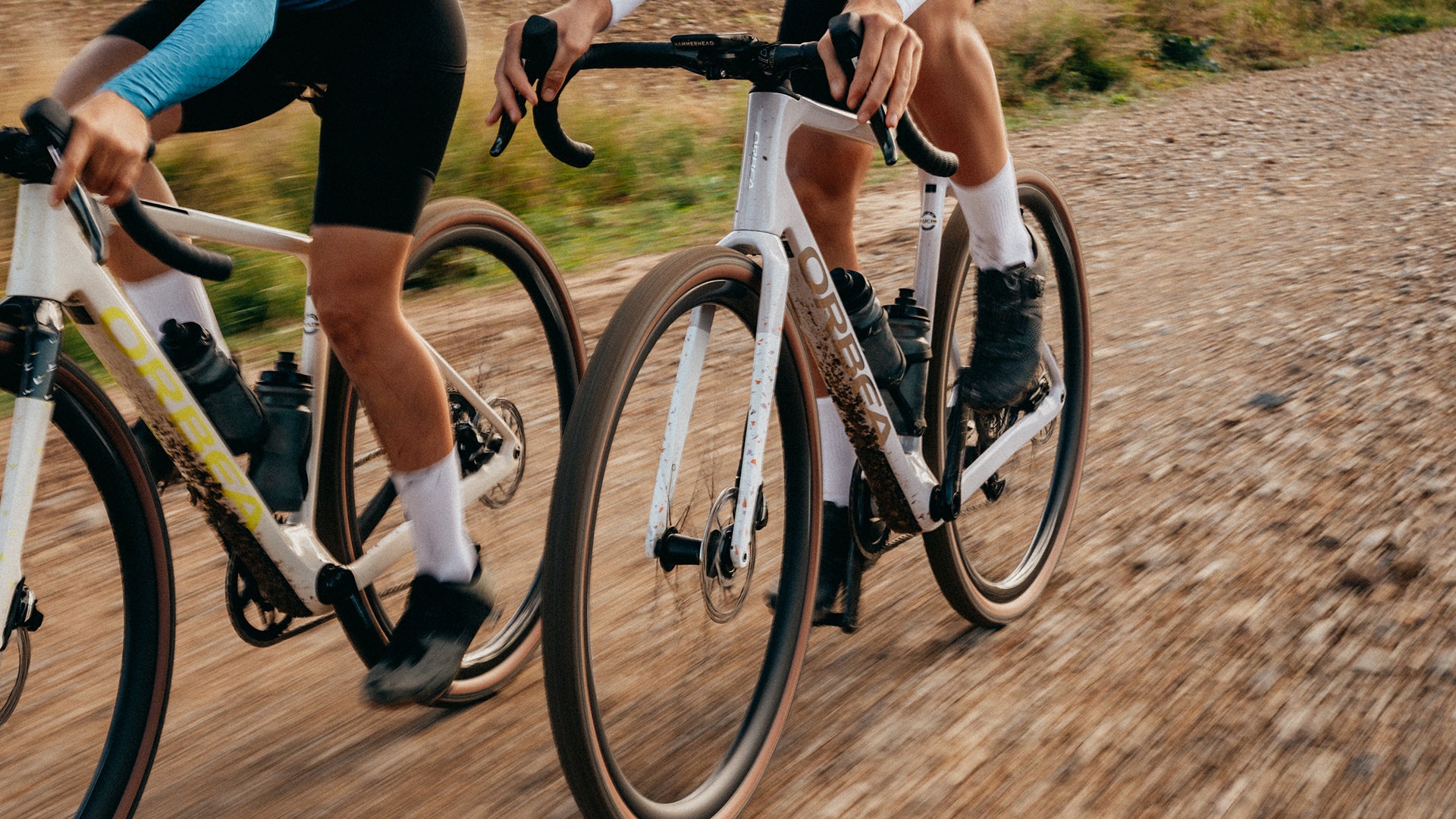 An Orbea Terra gravel bike with white paint, being ridden on a dirt road.