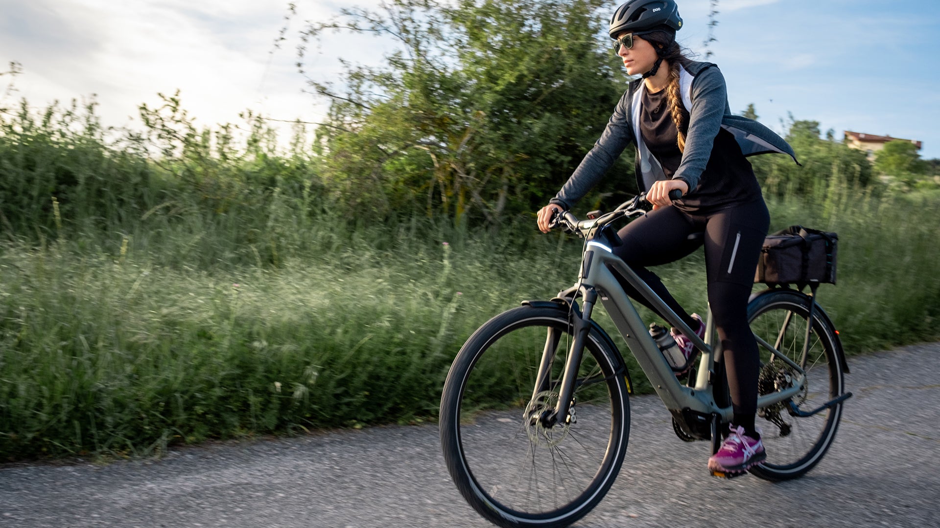 a woman riding an orbea kemen tour electric bike on a road. 