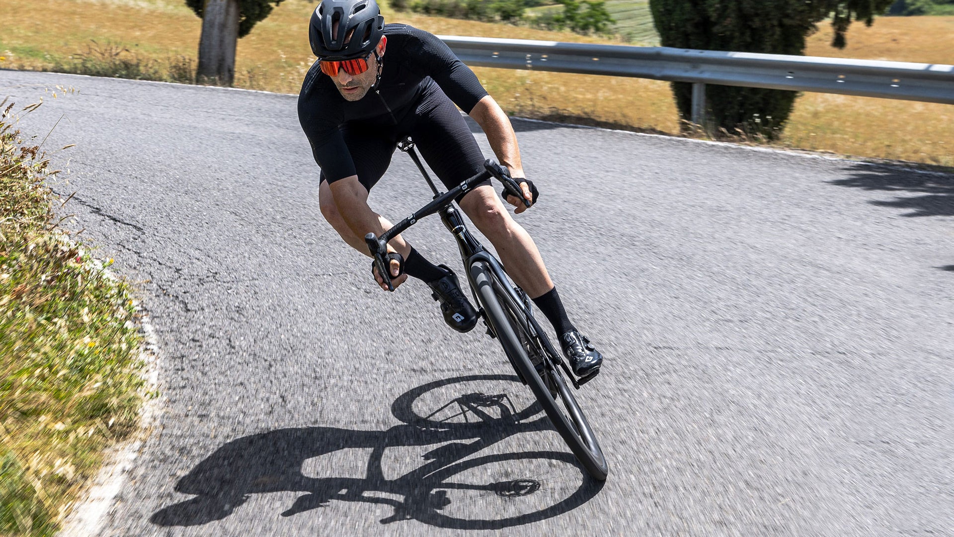 A Man riding the Pinarello Dogma x Road bike against some mountains