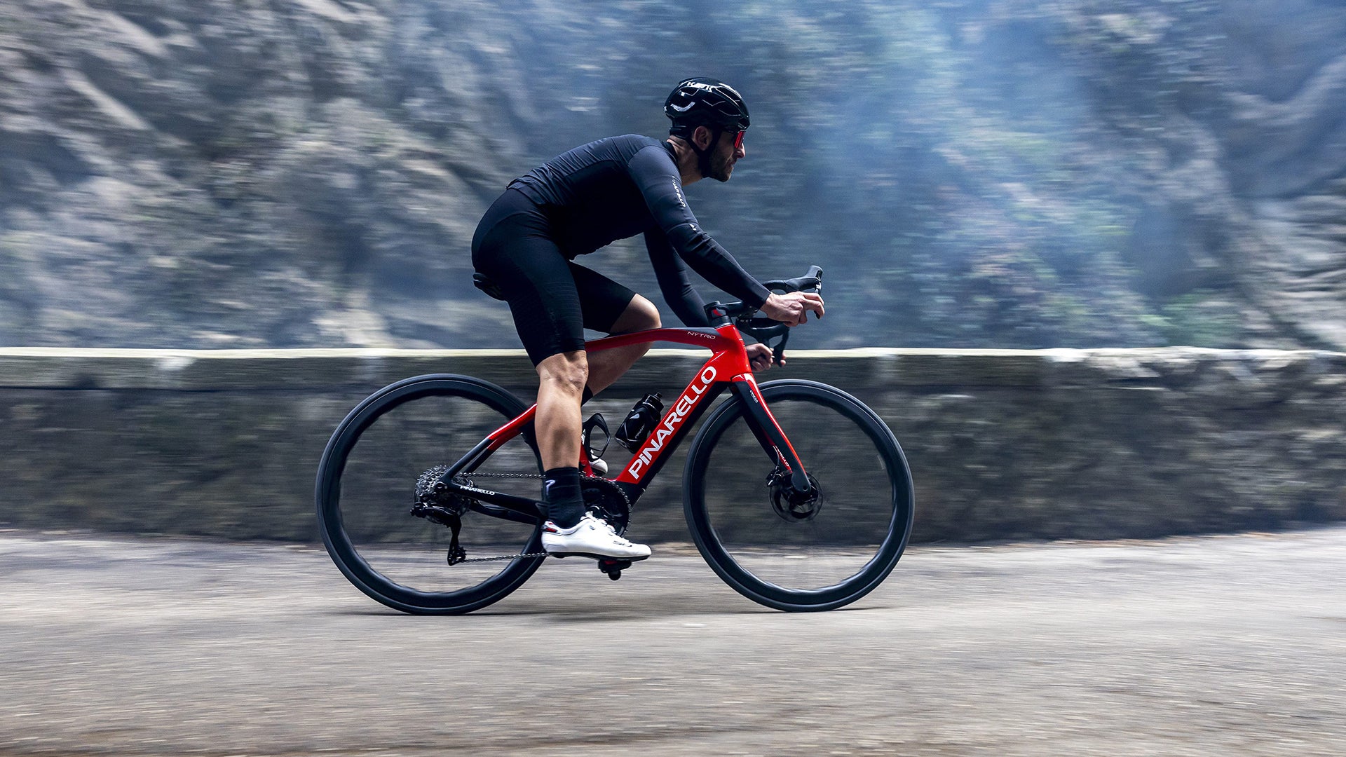 A Man riding the pinarello Nytro road electric bike on a paved road