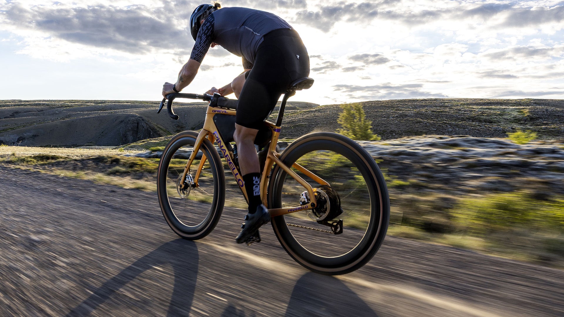 A woman riding the Pinarello Grevil gravel bike against some rolling hills