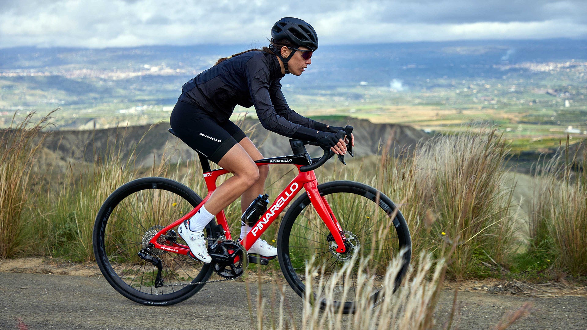A woman riding the Pinarello X Road bike against some mountains