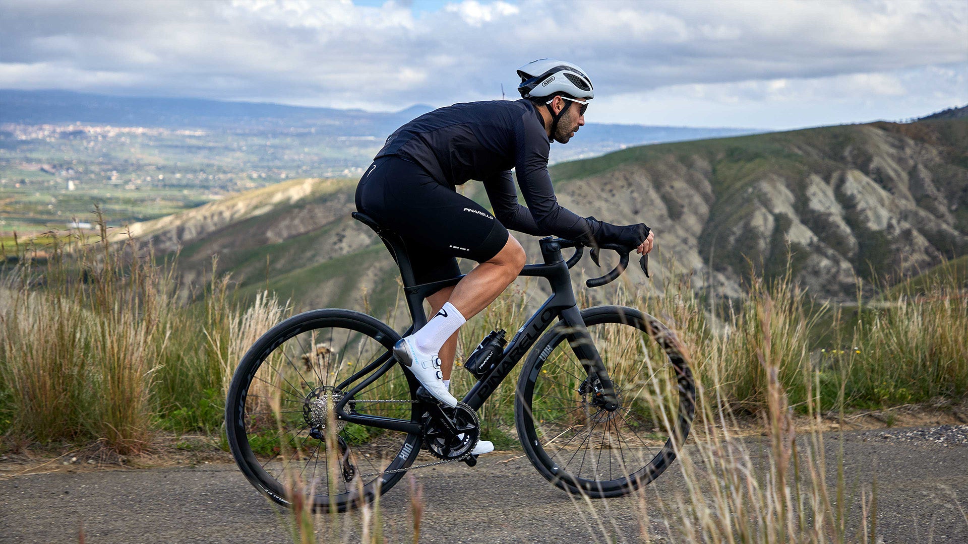 A Man riding the Pinarello X Road bike against some mountains