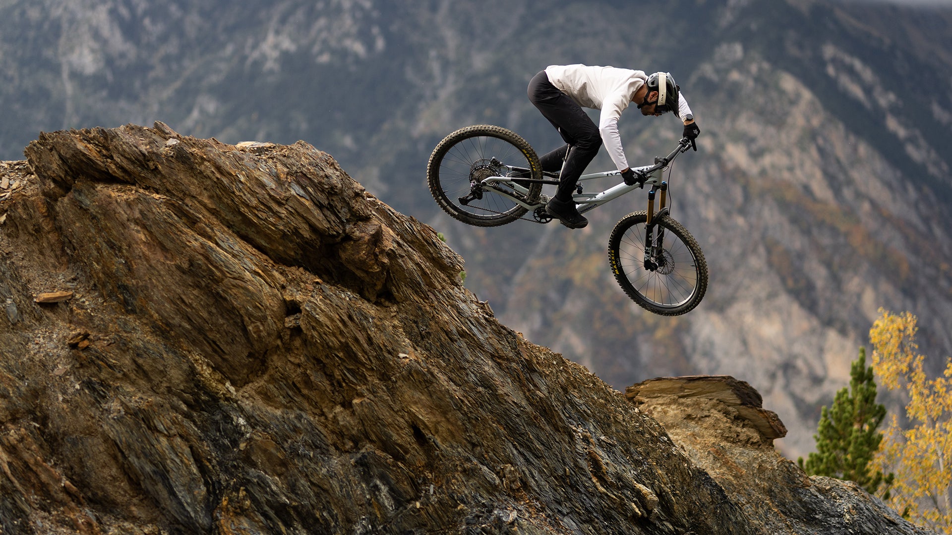 A man riding a Orbea Rallon Mountain bike own a rock cliff. 
