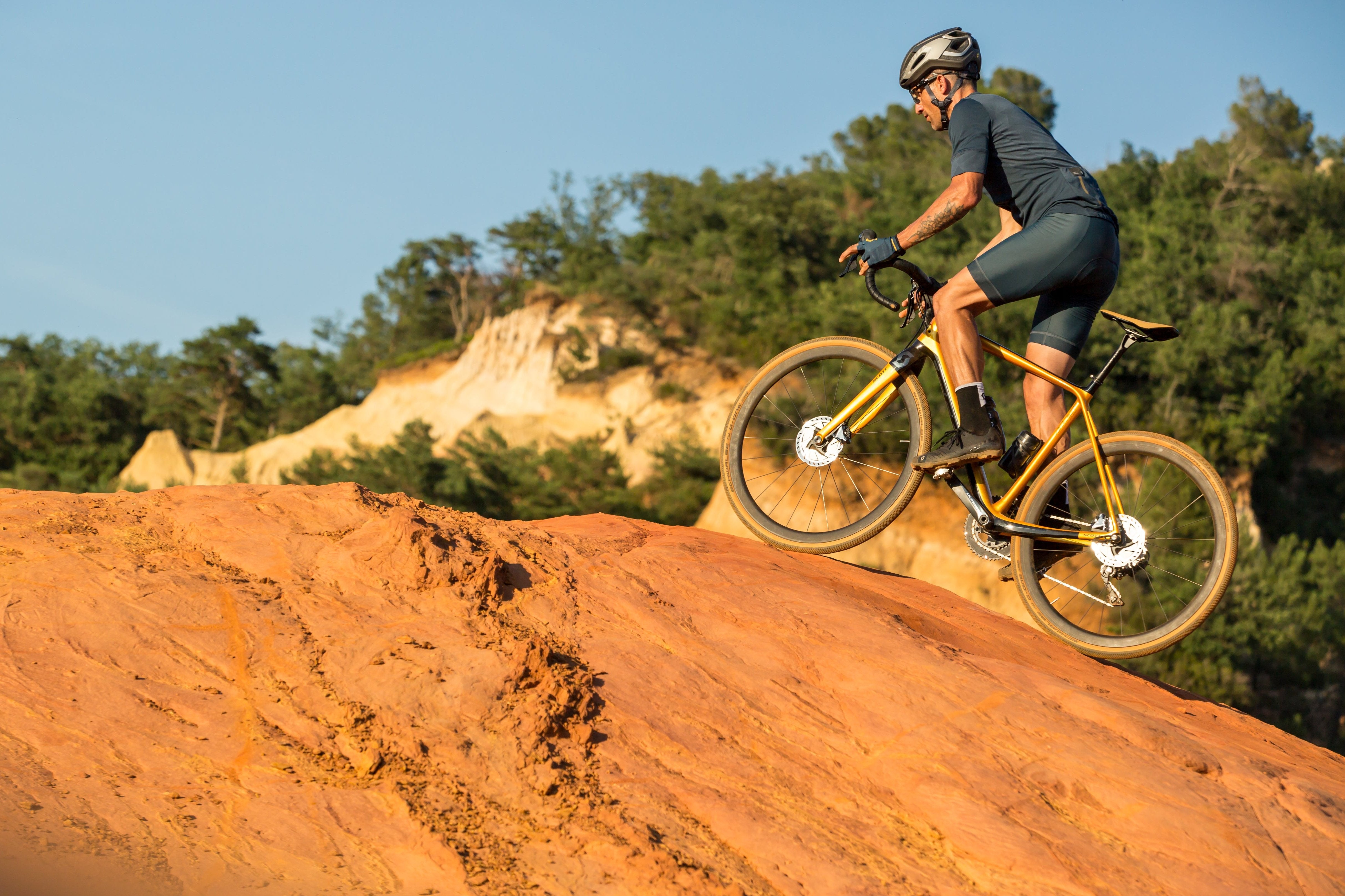A man riding the Scott Addict Gravel bike up a dirt hill.