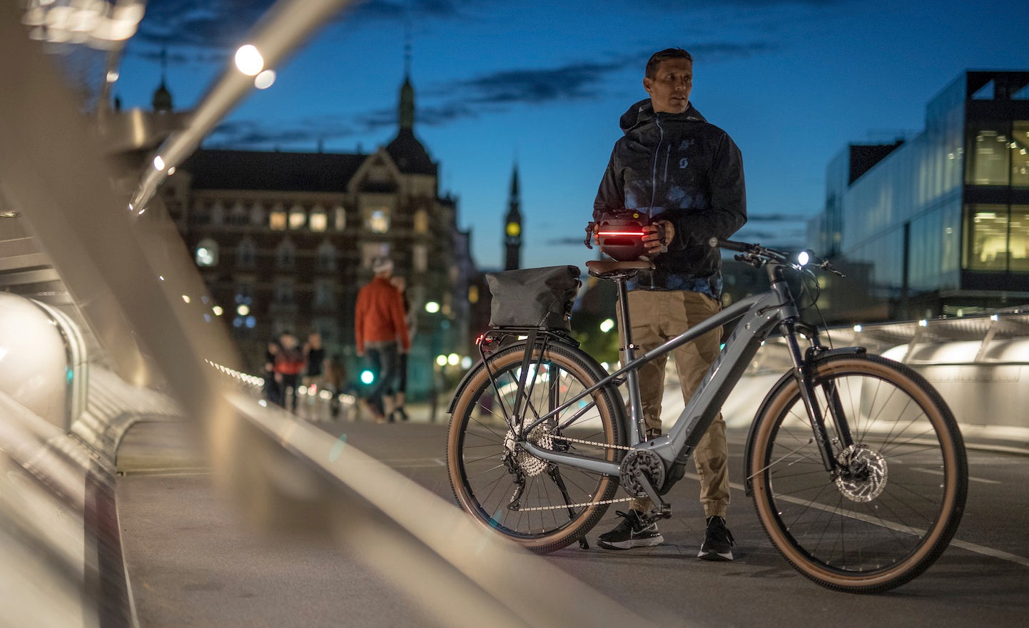 The A man with the SCOTT sub active eride bicycle standing in front of a city at night. Available at Contender Bicycles.