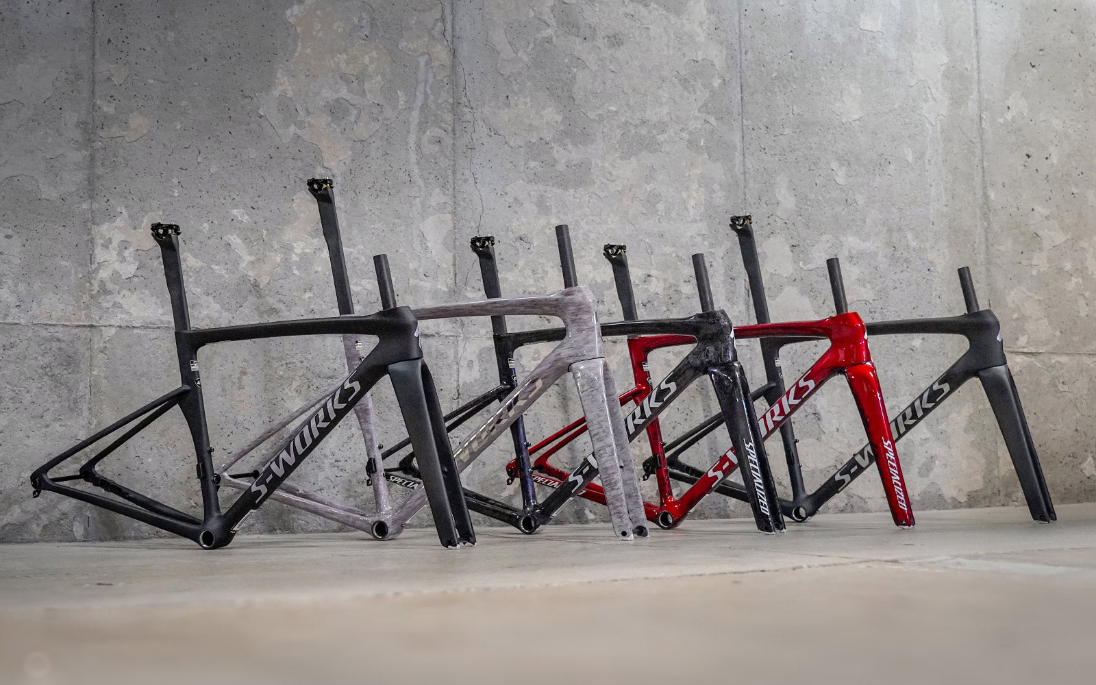 Five Specialized Tarmac SL9s lined up on a row with a concrete background.