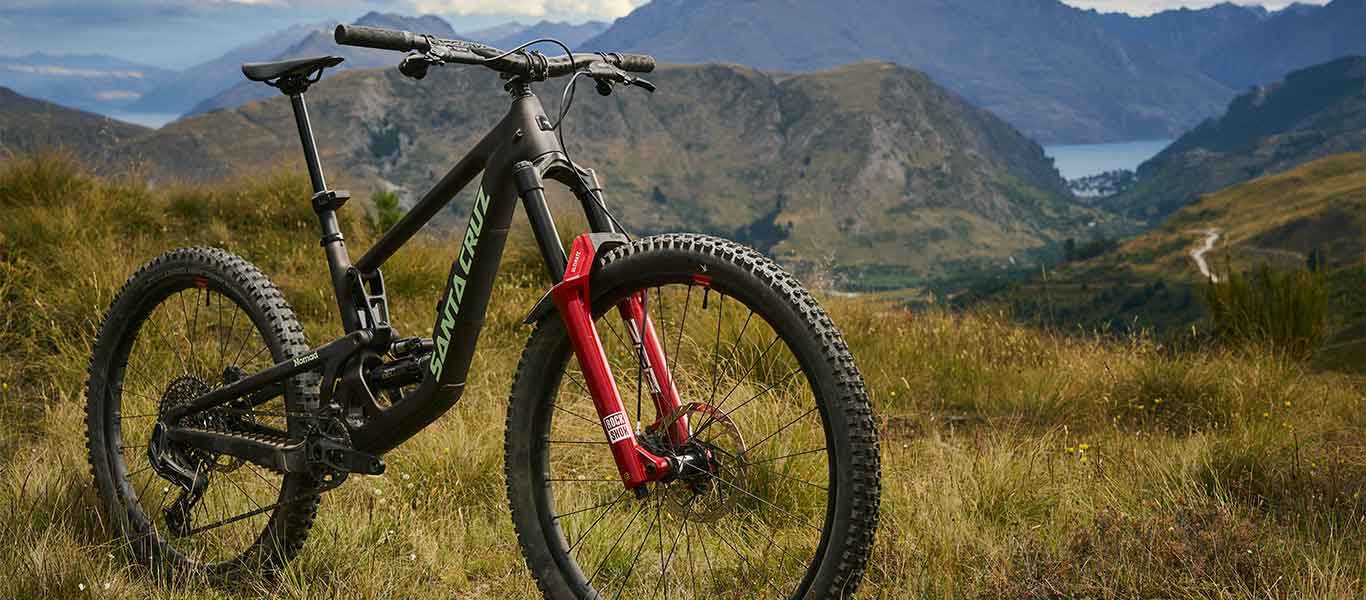 Mountain bike on a grassy hill with mountains and a lake in the background