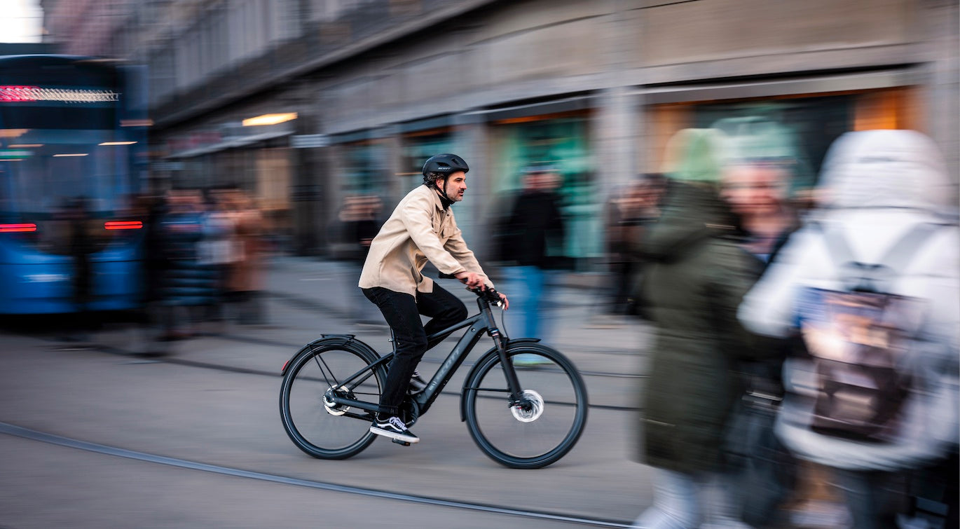 The A man riding the SCOTT sub active eride bicycle on a crowded city street. Available at Contender Bicycles.