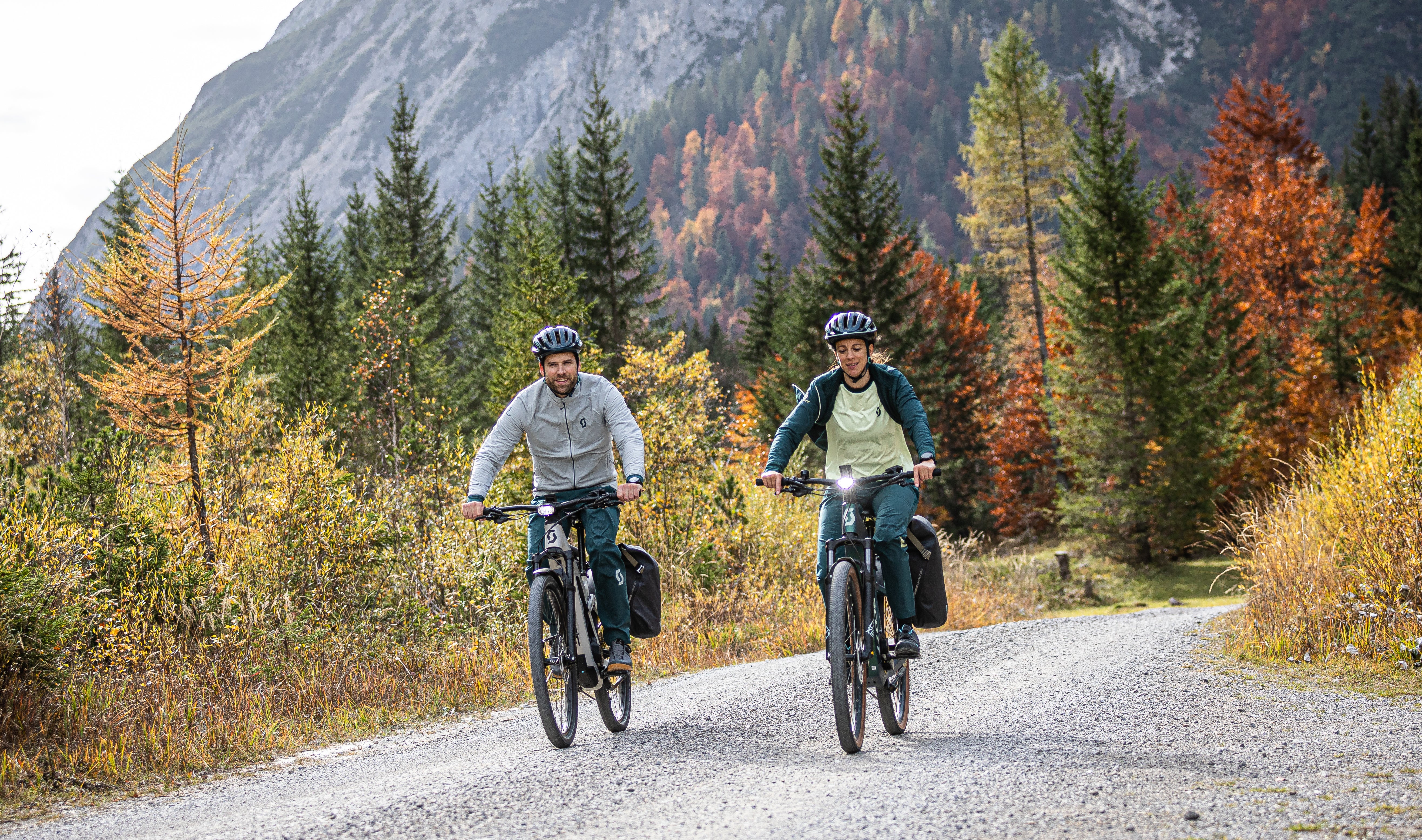 A couple riding the SCOTT sub active eride bicycle on a dirt road through a mountain range.  Available at Contender Bicycles.