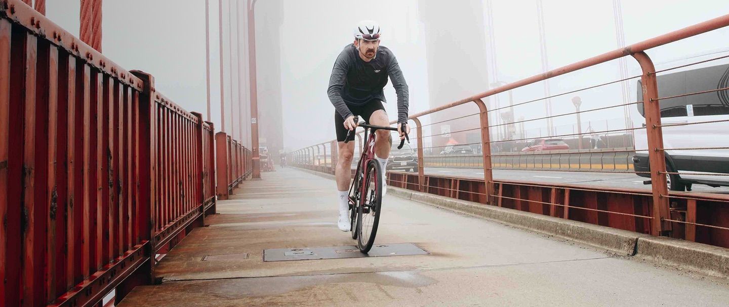 A man riding a red bike on the Golden Gate Bridge.