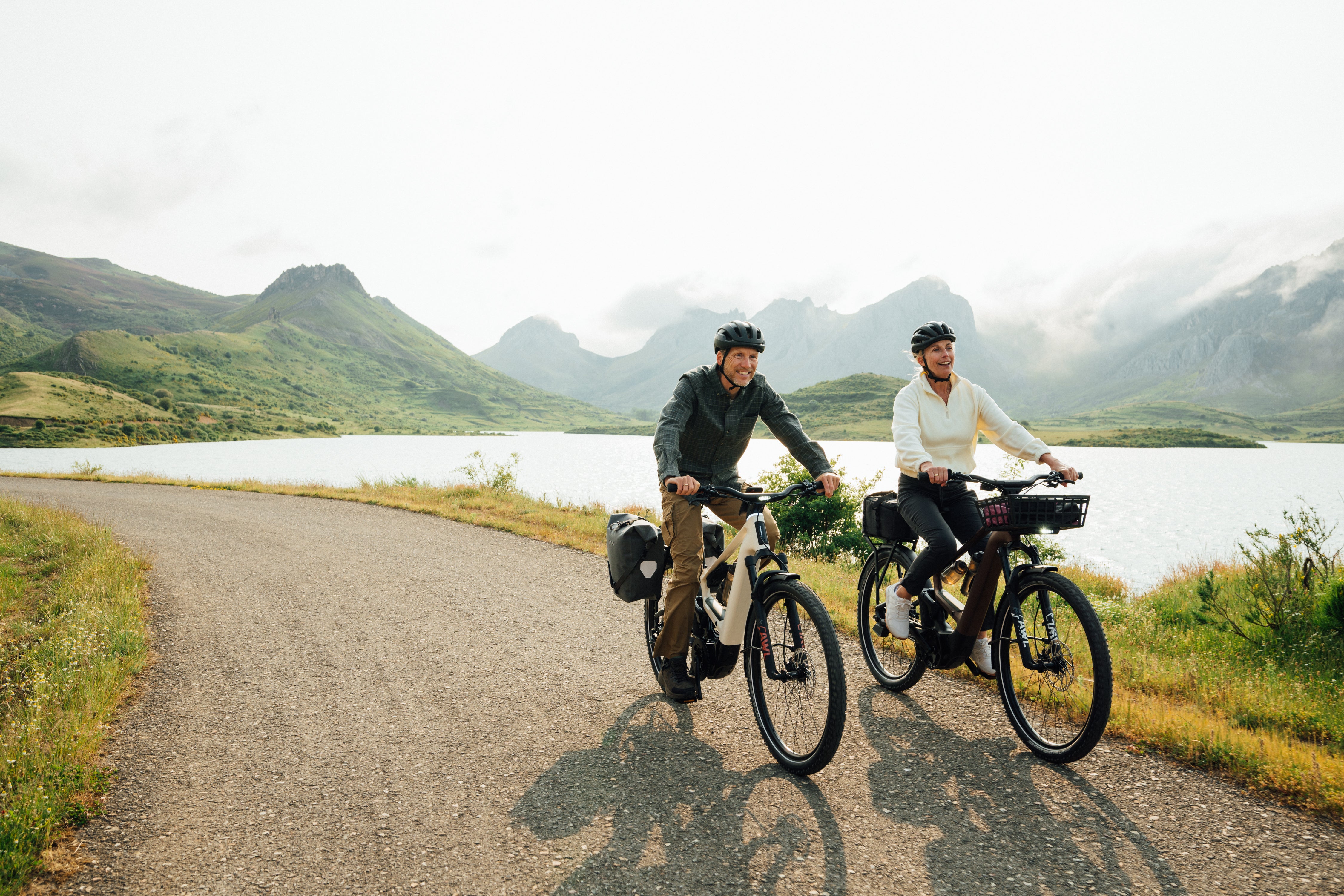 The Orbea Muga electric bicycle being ridden by 2 people by a lake.