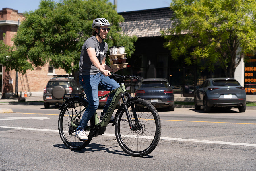 A man riding an Orbea Kemen E-Bike Commuter holding coffee