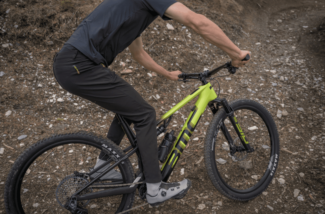 a man riding a bmc fourtstroke amp bicycle that is yellow and black on a dirt trail