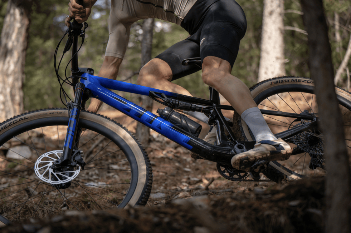 a man riding a blue bmc fourstroke mountain bike on a dirt trail