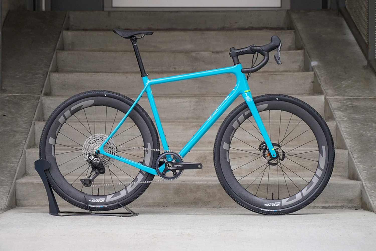 Turquoise bicycle on a stand with concrete steps in the background