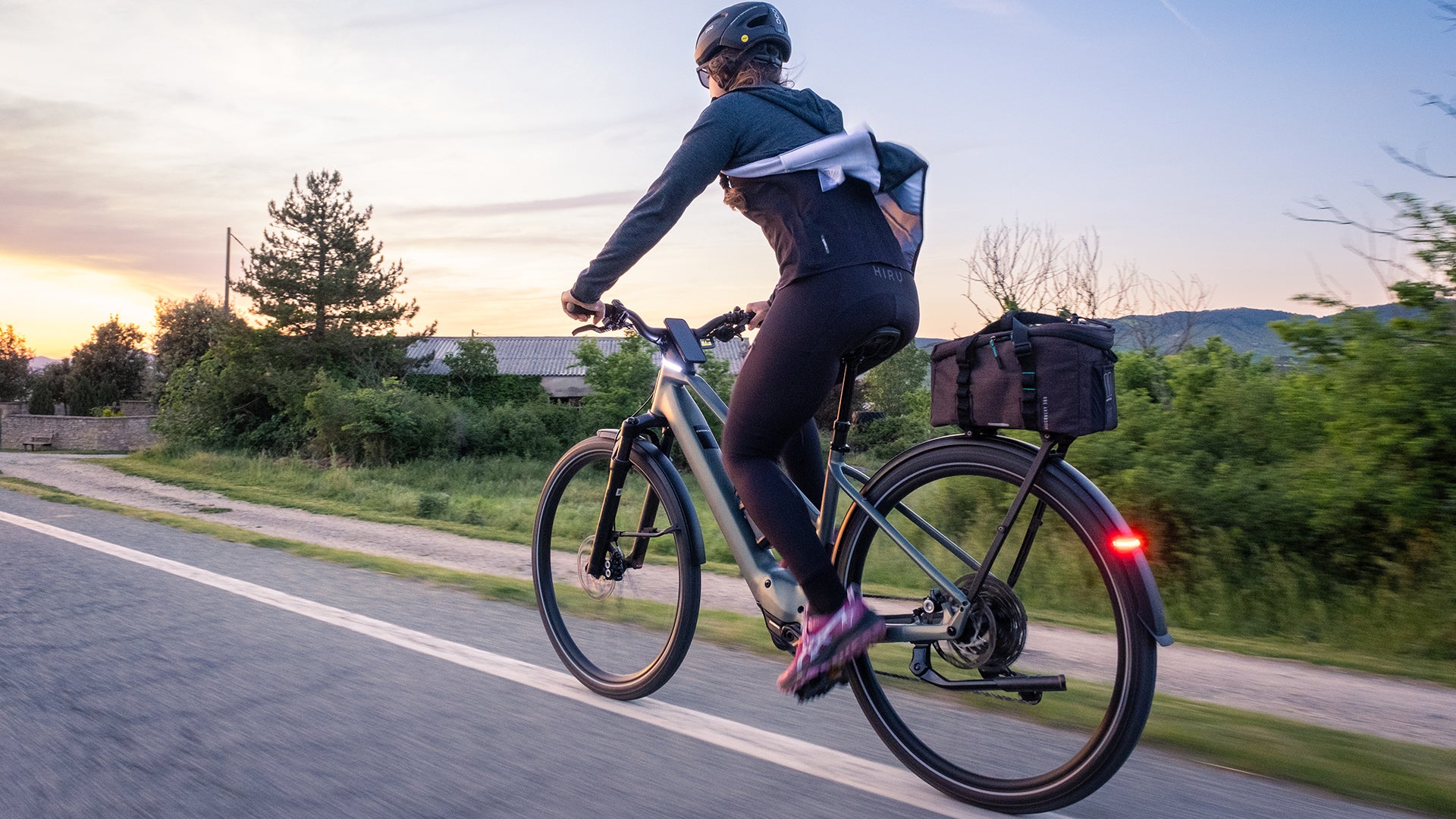 a woman riding an orbea kemen tour electric bike on a road. 