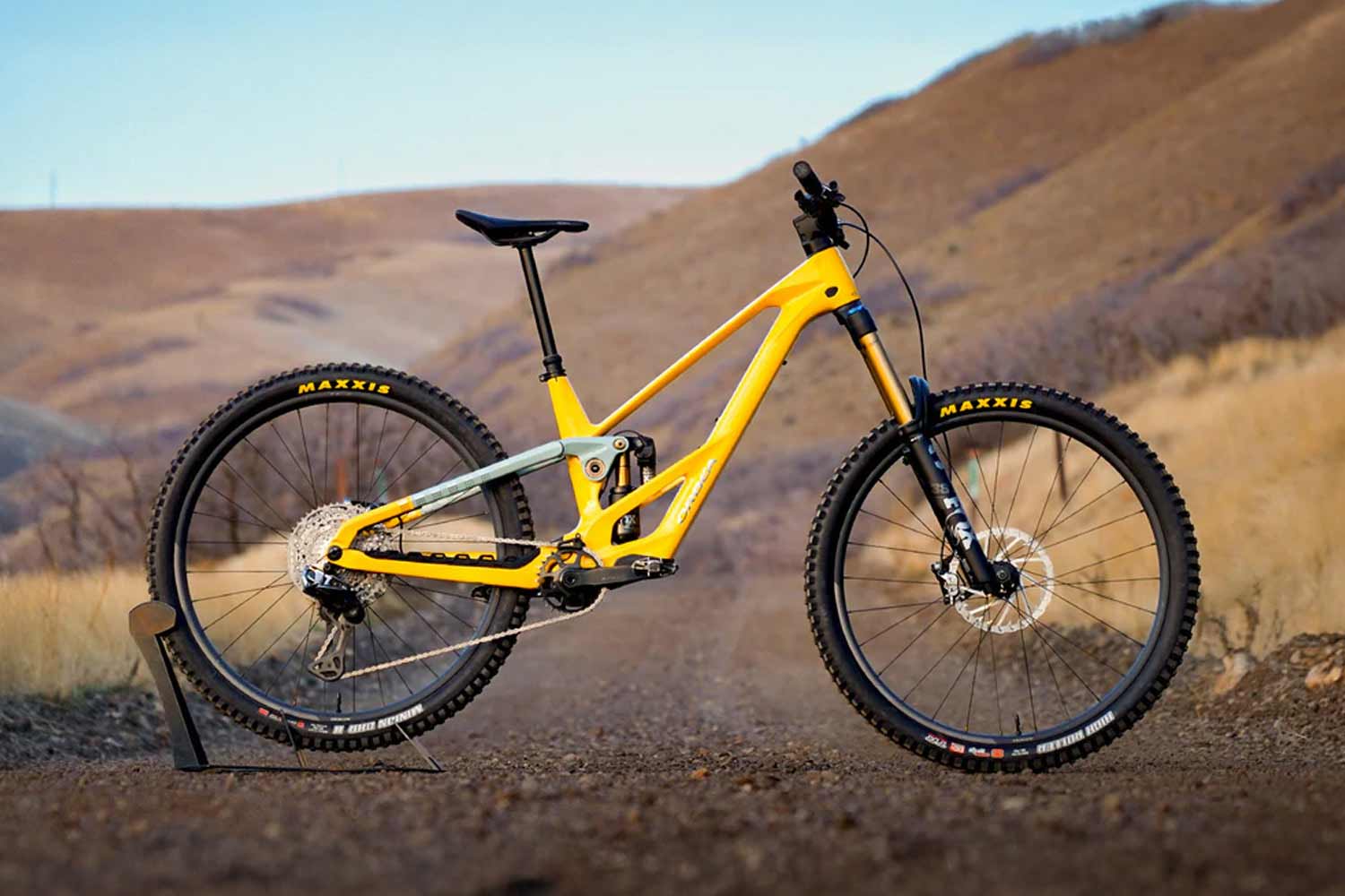 Yellow mountain bike on a dirt trail with a scenic background.