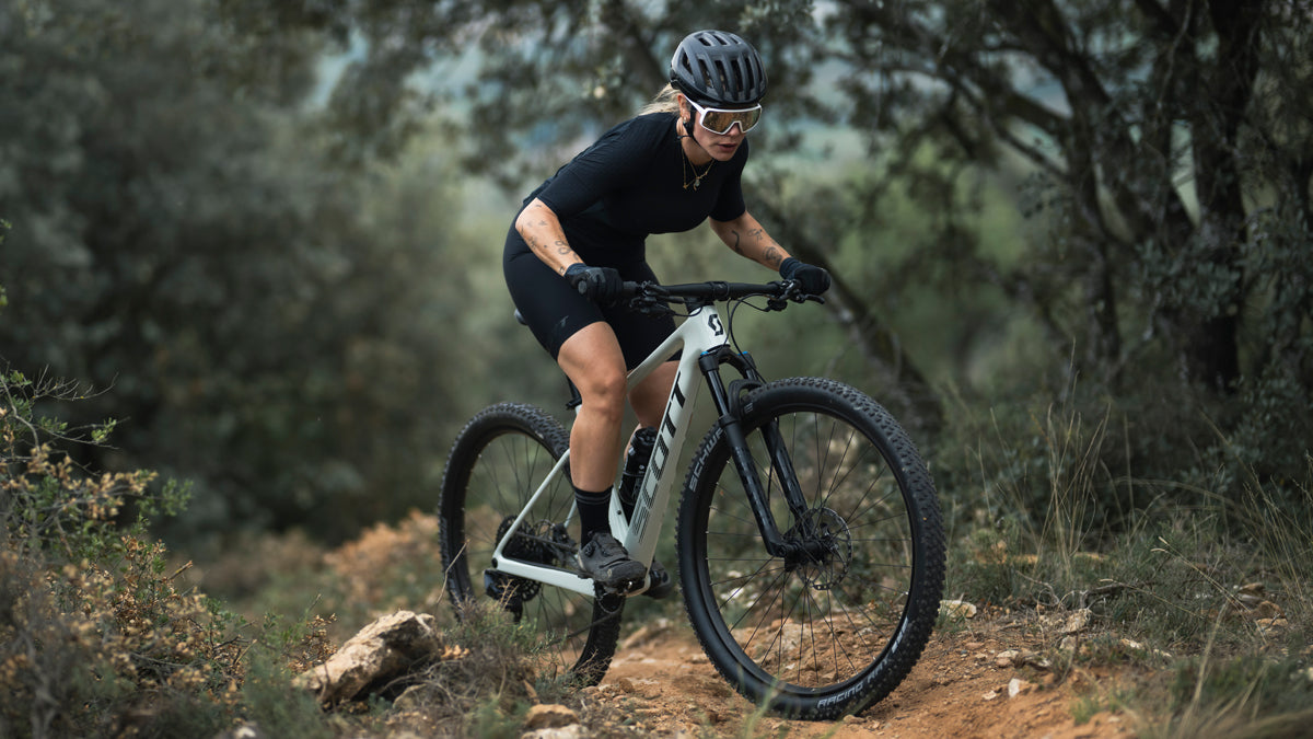 A woman riding the Scott Scale Mountain bike up a hill.